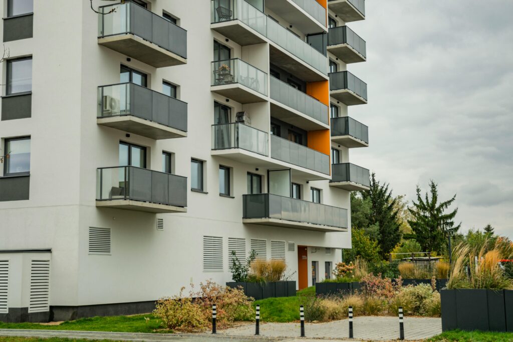 Contemporary apartment complex featuring glass balconies and landscaped surroundings.
